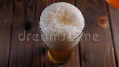 一名酒保在木制背景下将啤酒倒入玻璃杯中的特写镜头。